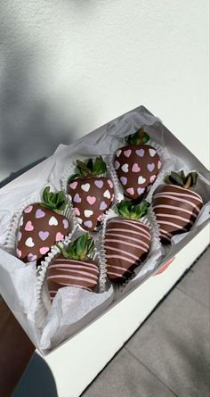 four chocolate covered strawberries in a white box