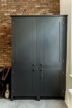 an armoire with two doors in front of a brick wall