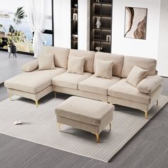 a living room with a sectional couch and footstool on the rug in front of it