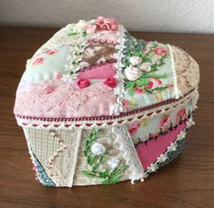 a decorative box sitting on top of a wooden table covered in lace and fabric flowers