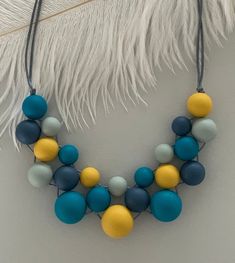 a blue and yellow necklace hanging from a white feather