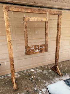 a wooden frame sitting in front of a garage door with snow falling on the ground