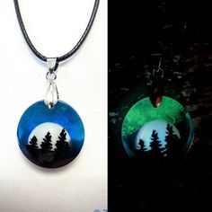 two different necklaces with trees in the middle and green light at the bottom, one is glowing