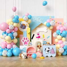 a dog is sitting in front of a birthday party with balloons and decorations on the floor