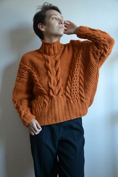 a man in an orange sweater is leaning against a wall with his hand on his head