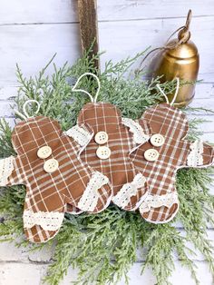 three brown and white plaid gingerbread cookies hanging from a christmas wreath with pine needles