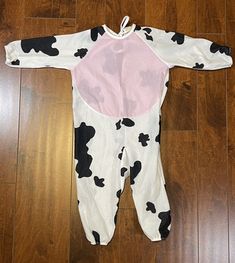 a baby's cow onesie laying on the floor next to a wooden floor