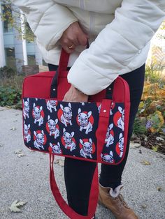 a woman holding a red and black bag with skulls on it's front pocket