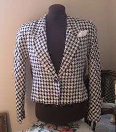 "Classic Blazer Vintage ladies size 4 in navy and cream fitted tapered bodice, broad textured weave, single fabric covered button at waist, Cropped length classic houndstooth, lapel chest pockets with folded and pinned hankie, fully lined, shoulders are  padded, lapels are rather wide, gently flared from waist button to bottom. Size Ladies/Misses Size 4 Fabric 40% silk 30% wool 20% Rayon 10% nylon Color Navy and cream large scale houndstooth  Made in  USA Waist 32\" Bottom 38\" at button flair B Fitted Houndstooth Tweed Jacket With Lapel Collar, Fitted Long Sleeve Houndstooth Tweed Jacket, Fitted Houndstooth Tweed Jacket With Long Sleeves, Fitted Semi-formal Outerwear With Houndstooth Pattern, Fitted Vintage Houndstooth Blazer, Vintage Fitted Houndstooth Blazer, Fitted Jacket, Usa Outfit, Classic Blazer