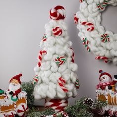 christmas decorations are displayed in front of a white wall and tree with candy canes on it