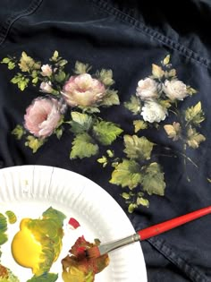 a white plate topped with flowers next to a painting brush and paper plate filled with paint