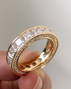 someone is holding a gold ring with white stones