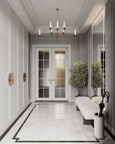 an elegant hallway with white walls and marble flooring, two planters on either side of the door