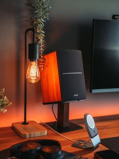 a wooden table with speakers and a light bulb on it next to a flat screen tv