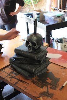 a skull sitting on top of a pile of books next to a person standing in the background