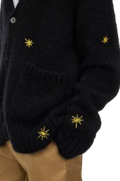 a man wearing a black sweater with gold stars on it