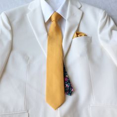 There is nothing like a versatile necktie that is solid on the front and a floral print tail to give your formal style an elegant and dapper touch. Simple and sophisticated make it the ideal neck tie to wear with most of your dress shirts and suits for any occasion.  Sold as a complete set:  necktie and pocket square Color:  Marigold Yellow Solid Front with Black Floral Print Tail (Back side)  Material:  100% Cotton Necktie:  approx. 2.75 inches wide and 58 inches long Pocket Square:  approx. 12 Dapper Solid Color Tie For Wedding, Dapper Solid Color Wedding Ties, Dapper Wedding Tie In Solid Color, Dapper Wedding Tie, Dapper Suit And Tie Accessories For Wedding, Classic Yellow Suits For Semi-formal Occasions, Classic Groom Ties, Formal Fitted Gold Neckwear, Gold Fitted Neckwear For Formal Occasions