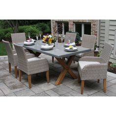 a dining table with chairs and plates on it in front of a brick patio area