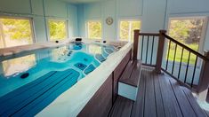 an indoor hot tub in the middle of a wooden floored area with windows and railings