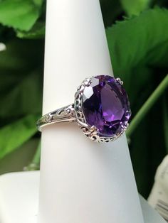 "Natural Purple Amethyst Ring Description Edward Design#70 (smaller version) MADE TO ORDER Inspired by Edwardian jewelry of the early 1900s, I now offer this lovely Antique reproduction ring in sterling silver. This gorgeous ring is set with a stunning 3.32ct Natural purple amethyst gemstone. This genuine amethyst has excellent color and clarity. The oval cut amethyst is 12mm (1/2th of an inch) Long by 10mm Wide (3/8th\"). The ring sits 6mm off the finger. The inside of the band s marked 925 for Oval Purple Filigree Amethyst Ring, Oval Purple Amethyst Ring With Filigree, Purple Oval Amethyst Ring With Filigree, Elegant Oval Solitaire Gemstone, Purple Oval Filigree Rings, Classic Oval Amethyst Ring With Accent Stones, Oval Amethyst Ring With Intricate Design, Oval Gemstone Filigree Ring For Formal Events, Oval Hallmarked Amethyst Ring In White Gold