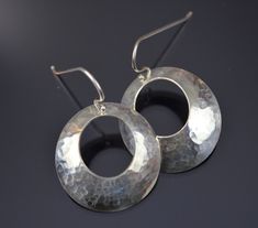 "Starting with 1\" sterling discs, a circle is punched out of the middle to create a donut.  The metal is hammered and then pressed into a dome shape.  Sterling ear wires are added.  Very light weight, simple, and pretty.  These earrings could go with anything--casual to formal." Hammered Sterling Silver Round Disc Earrings, Hammered Silver Round Disc Earrings, Hammered Sterling Silver Round Earrings, Sterling Silver Hammered Round Earrings, Modern Hammered Open Circle Earrings, Hand Forged Sterling Silver Round Hoop Earrings, Hand Forged Sterling Silver Round Disc Jewelry, Artisan Hand Forged Round Hoop Earrings, Hammered Metal Circle Hoop Earrings