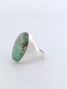 This striking sterling silver ring by Rob Sherman features a large oval signet design, showcasing a luscious New Lander turquoise cabochon. The stone boasts a unique minty green hue with a chocolate matrix, making it a truly eye-catching piece. Handcrafted with precision, this ring is perfect for those who appreciate high-quality, one-of-a-kind jewelry. Sterling silver ring with New Lander turquoise cabochon Large oval signet-style design for a bold look Mint green turquoise with a stunning chocolate matrix Handmade by artisan Rob Sherman Size 8.5, ideal for medium-sized fingers or as a statement ring Perfect for collectors of unique, handcrafted turquoise jewelry Versatile piece that adds style to both casual and formal outfits PERFECTION. EVERY TIME.At Rob Sherman Designs, we believe in Modern Turquoise Ring With Polished Finish, Modern Oval Turquoise Jewelry, Modern Turquoise Oval Jewelry, Large Oval Turquoise Stone Ring, Oval Turquoise Ring With Large Stone, Elegant Oval Turquoise Ring With Large Stone, Modern Turquoise Round Ring, Elegant Green Turquoise Ring, Handmade Classic Oval Turquoise Ring