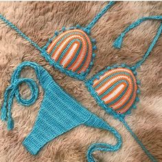 two crocheted swimsuits are laying on a furry surface, one is blue and the other is orange