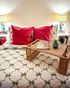 a bed with two red pillows on top of it and a coffee table in the middle