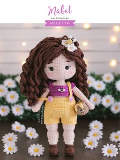 a crocheted doll is standing in front of daisies