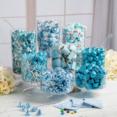 blue and white candies in clear vases with candy sticks on the table next to them