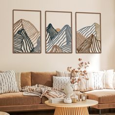 a living room with two couches and three paintings on the wall above them, in front of a coffee table