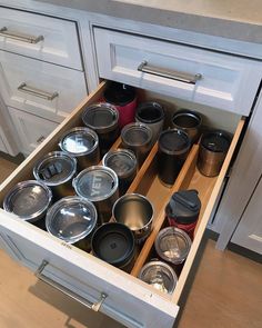 an open drawer in a kitchen filled with lots of pots and pans on it