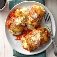 a white plate topped with meat covered in marinara sauce next to a glass of wine