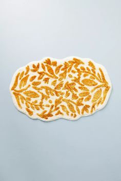 an orange and white rug with leaves on it in the shape of a leaf, against a light blue background