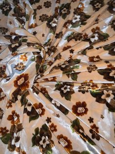 the fabric has flowers on it and is white with brown, yellow and green colors