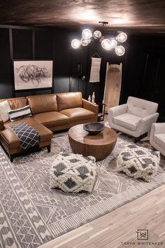 a living room with couches, chairs and rugs on the floor in front of black walls