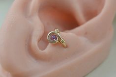 a gold ring with an amethyst stone in it's center sits on top of a pink ear