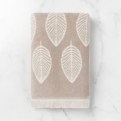 a towel with leaves on it sitting on top of a marble countertop next to a white wall