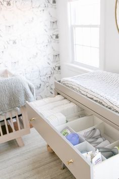 an open drawer in the middle of a bed with a mirror above it and a baby's crib