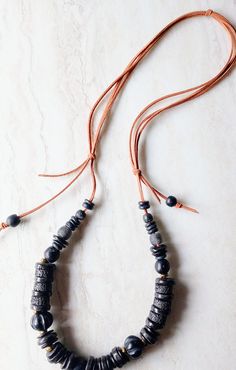 "Dark, organic, classic, everyday and everywhere. This necklace is 30\" in length. Soft beige-brown cord and array of black beads, disks, and spacers. This necklace is a staple wardrobe all year long. Would be beautiful on linen. Black African Recycled Glass beads in 12mm to 22mm in size.  Also a variety of wood beads, black disks, recycled glass beads, and fused glass. Full of interest and texture. Soft leather suede in natural beige-brown in this pull over head design. One-of-a-kind. The item/ Adjustable Artisan Beaded Necklaces, Artisan Black Adjustable Beaded Necklaces, Artisan Black Adjustable Beaded Necklace, Artisan Black Beaded Necklaces With Adjustable Fit, Adjustable Black Artisan Beaded Necklace, Adjustable Brown Necklace With Black Beads, Adjustable Brown Necklaces For Everyday Use, Handmade Black Beaded Necklaces For Everyday, Adjustable Earthy Necklace For Everyday Wear