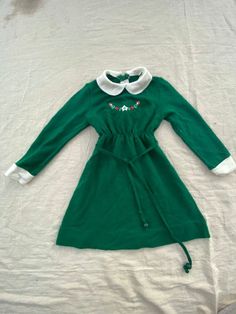 "vintage 1970s dress * toddler size four * long sleeve with white ends * mini collar * ties around the waist with green beads on the end * beautiful embroidery on the front with a white flower and vine with red flowers and green leaves * zipper in the back * brand: little world measurements (inches) * 20\" long * 12\" wide * 5\" tall armpit * 2\" tall collar * 12\" long sleeve  * 12-20\" waist preloved but in great vintage condition with no major apparent flaws Thank you for looking! Browse the rest of my shop for more bohemian vintage lovelies!" Long Sleeve Green Dress, Sleeve Green Dress, Green Long Sleeve Dress, 1970s Dress, Dress Christmas, 1970s Dresses, Christmas Floral, Boho Vintage, Floral Flower