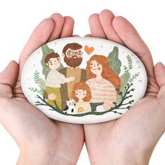 two hands holding a painted rock with family pictures on it