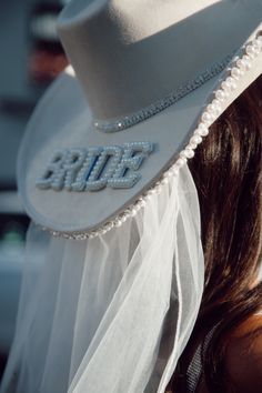 a woman wearing a white hat with the word bride on it's brim