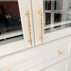 a white cabinet with gold handles and knobs