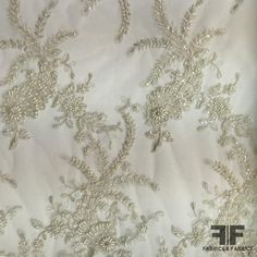 Couture Floral Beaded Netting - Ivory/Silver (Bridal) Color - White Ivory Silver Width - 50/51” Fabric Care - Dry Clean Only Elegant Gold Wedding Dress For Festive Occasions, Gold Wedding Dress With Zari Work For Ceremony, Festive White Fabric With Pearl Embroidery, Festive White Embroidered Fabric With Pearls, Silver Embroidered Fabric For Festive Occasions, Fitted Silver Embroidered Fabric For Festive Occasions, Cream Embroidered Fabric For Festive Formal Occasions, Festive Cream Embroidered Fabric For Formal Occasions, Elegant Gold Wedding Dress With Zari Work