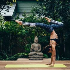 a woman is doing a handstand on a yoga mat in front of a buddha statue