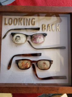 three pairs of eyeglasses are displayed in a shadow box that says looking back