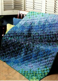 a blue and green quilt sitting on top of a wooden table next to a window