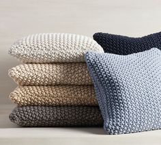 four knitted pillows stacked on top of each other in various colors and sizes,