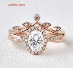 a wedding band with an oval cut diamond surrounded by smaller round diamonds and leaves on each band